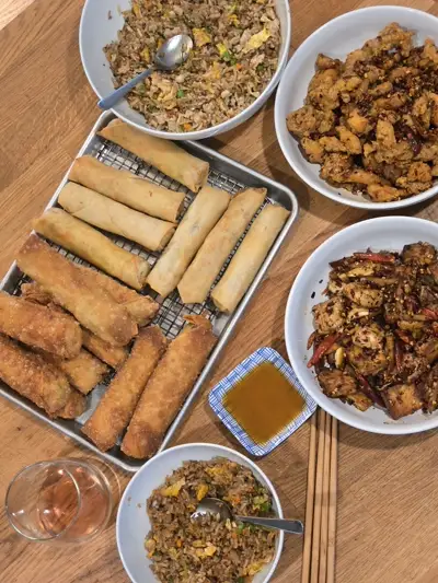Chinese feast spread featuring egg rolls, kung pao chicken, and fried rice — global cuisine by Chef Mollie